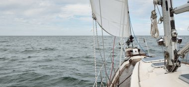 Fırtınada açık denizde yelken açan eski klasik bir yat. Tahta meşe güvertesi. Ketçap yelkenli. Dalgalar, su sıçramaları. Gezi, tatil, yelkenli yarışı, spor, boş zaman aktivitesi.