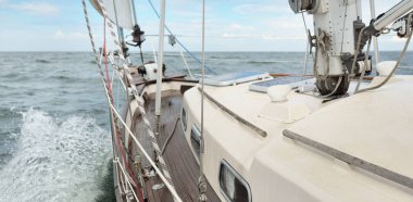 Fırtınada açık denizde yelken açan eski klasik bir yat. Tahta meşe güvertesi. Ketçap yelkenli. Dalgalar, su sıçramaları. Gezi, tatil, yelkenli yarışı, spor, boş zaman aktivitesi.