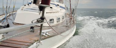 Fırtınada açık denizde yelken açan eski klasik bir yat. Tahta meşe güvertesi. Ketçap yelkenli. Dalgalar, su sıçramaları. Gezi, tatil, yelkenli yarışı, spor, boş zaman aktivitesi.