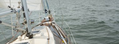 Fırtınada açık denizde yelken açan eski klasik bir yat. Tahta meşe güvertesi. Ketçap yelkenli. Dalgalar, su sıçramaları. Gezi, tatil, yelkenli yarışı, spor, boş zaman aktivitesi.