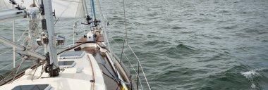 Fırtınada açık denizde yelken açan eski klasik bir yat. Tahta meşe güvertesi. Ketçap yelkenli. Dalgalar, su sıçramaları. Gezi, tatil, yelkenli yarışı, spor, boş zaman aktivitesi.