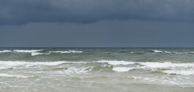 Fırtına sırasında açık bir Baltık denizi. Dramatik gökyüzü, karanlık, parlak bulutlar. Dalgalar, su sıçramaları. Idyllic deniz manzarası. Kış, iklim değişikliği, doğa, kararsız hava, tehlike