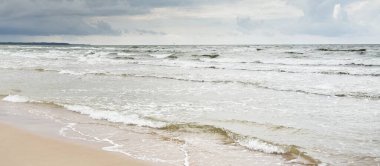 Fırtınadan sonra Baltık kıyıları. Dramatik gökyüzü, parlayan bulutlar. Resimli panoramik manzara. Doğa, çevre, ekoloji, eko-turizm, yürüyüş, keşif kavramları