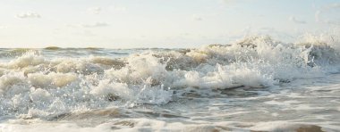 Fırtınadan sonra Baltık kıyıları. Gün batımı, yumuşak altın güneş ışığı. Su yüzeyi dokusu, çarpan dalgalar ve sıçramalar, köpük. Resimli panoramik manzara. Idyllic deniz manzarası. Doğa, çevre, ekoloji