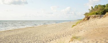 Fırtınadan sonra Baltık kıyıları. Gün batımı, yumuşak güneş ışığı, parlayan bulutlar. Resimli panoramik manzara. Doğa, çevre, ekoloji, eko-turizm, yürüyüş, keşif kavramları