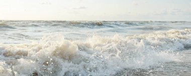 Fırtınadan sonra Baltık kıyıları. Gün batımı, yumuşak altın güneş ışığı. Su yüzeyi dokusu, çarpan dalgalar ve sıçramalar, köpük. Resimli panoramik manzara. Idyllic deniz manzarası. Doğa, çevre, ekoloji