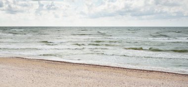Fırtınadan sonra Baltık kıyıları (kum tepeleri, plaj). Dramatik gökyüzü, parlayan bulutlar. Resimli panoramik manzara. Doğa, çevre, ekoloji, eko-turizm, yürüyüş, keşif kavramları