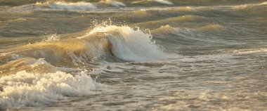 Fırtınadan sonra Baltık kıyıları. Gün batımı, yumuşak güneş ışığı. Su yüzeyi dokusu, çarpan dalgalar ve sıçramalar, köpük. Resimli panoramik manzara, arka plan. Doğa, çevre, ekoloji kavramları