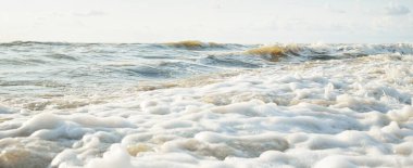 Fırtınadan sonra Baltık kıyıları. Gün batımı, yumuşak altın güneş ışığı. Su yüzeyi dokusu, çarpan dalgalar ve sıçramalar, köpük. Resimli panoramik manzara. Idyllic deniz manzarası. Doğa, çevre, ekoloji