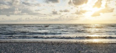 Fırtınadan sonra Baltık kıyıları. Gün batımı, yumuşak güneş ışığı, parlayan bulutlar. Resimli panoramik manzara. Doğa, çevre, ekoloji, eko-turizm, yürüyüş, keşif kavramları