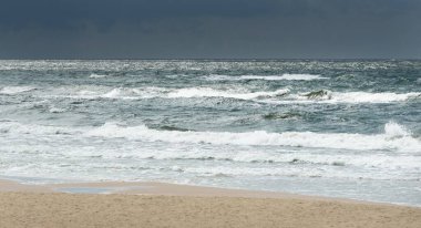 Fırtınadan sonra Baltık kıyıları (kum tepeleri, plaj). Dramatik gökyüzü, parlayan bulutlar. Resimli panoramik manzara. Doğa, çevre, ekoloji, eko-turizm, yürüyüş, keşif kavramları