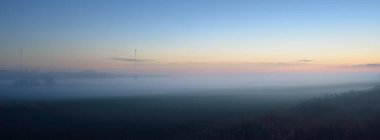 Gün batımında sisli bir arazide (orman çimenliği, çayır). Ayın doğuşu, alacakaranlık, karamsar gökyüzü. Idyllic yaz kırsal manzarası. Doğa, çevre, ekoloji, sessizlik, yalnızlık kavramları