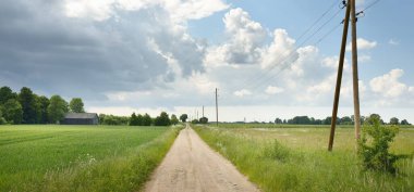 Fırtınadan sonra tarladan geçen boş köy yolu. Arabadan bir manzara. Idyllic kırsal kesim. Renkli, parlayan günbatımı bulutları. Ulaşım, yolculuk, özgürlük, seyahat tutkusu, uzak yerler kavramları.
