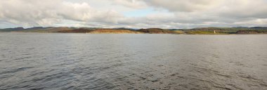 İskoçya, Rothesay 'ın kayalık kıyıları, tepeleri ve vadileri üzerinde dramatik bir gökyüzü. Yelkenliden panoramik manzara. Seyahat merkezleri, turizm, yürüyüş, dönüm noktası, ekoloji, çevre, doğa temaları