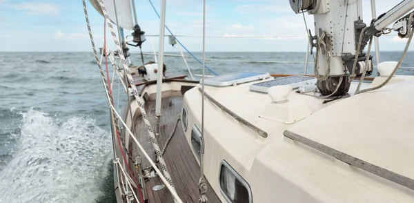 Fırtınada açık denizde yelken açan eski klasik bir yat. Tahta meşe güvertesi. Ketçap yelkenli. Dalgalar, su sıçramaları. Gezi, tatil, yelkenli yarışı, spor, boş zaman aktivitesi.