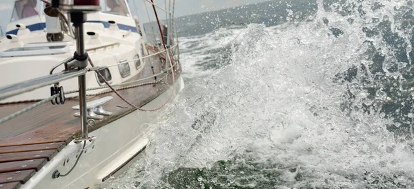 Fırtınada açık denizde yelken açan eski klasik bir yat. Tahta meşe güvertesi. Ketçap yelkenli. Dalgalar, su sıçramaları. Gezi, tatil, yelkenli yarışı, spor, boş zaman aktivitesi.