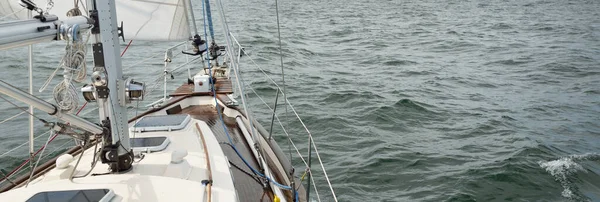 Fırtınada açık denizde yelken açan eski klasik bir yat. Tahta meşe güvertesi. Ketçap yelkenli. Dalgalar, su sıçramaları. Gezi, tatil, yelkenli yarışı, spor, boş zaman aktivitesi.