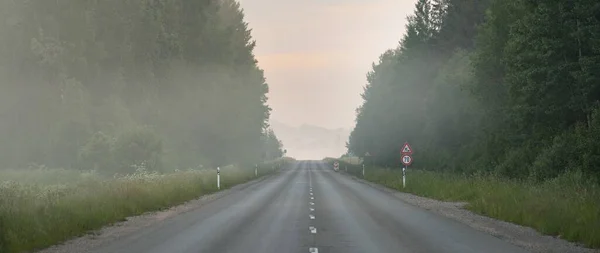 乡间公路 旧沥青路 在日出时穿过田野和森林 柔和的阳光 明亮的粉色和金色的云彩 边远地区 — 图库照片