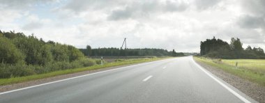 Tarlalar ve orman boyunca (asfalt yol) yol. Arabadan bak. Dramatik fırtına bulutları. Seyahat yerleri, rotalar, tatiller, lojistik, uzak yerler