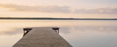 Forest lake (river) at sunset. Wooden pier. Glowing clouds, symmetry reflections in a still crystal clear water. Idyllic landscape. Nature, ecology, ecological reserve, ecotourism, hiking, vacations