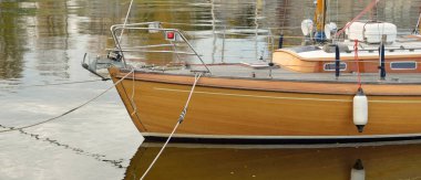 Modern klasik ahşap İsveçli yelkenli teknesi yat limanındaki bir iskeleye demirlemiş. Turizm, tatiller, boş zaman aktiviteleri, eğlence, yelkencilik temaları