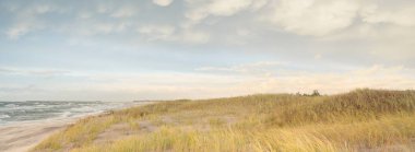 Baltic sea shore at sunset. Beach, sand dunes, dune grass. Clear sunset sky, glowing clouds. Idyllic landscape. Nature, vacations, recreation. eco tourism