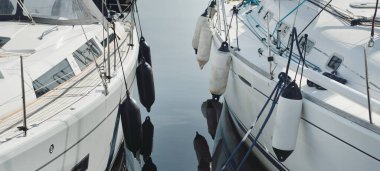 White modern sailboat (for rent and sale) moored to a pier in a yacht marina. Nautical vessel, transportation, amateur sailing, sport, leisure activity, vacations, cruising, recreation concepts