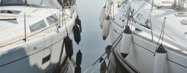 White modern sailboat (for rent and sale) moored to a pier in a yacht marina. Nautical vessel, transportation, amateur sailing, sport, leisure activity, vacations, cruising, recreation concepts