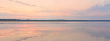 Gün batımında Orman Gölü. Yumuşak güneş ışığı, parlayan bulutlar kristal berrak suda simetri yansımaları. Idyllic manzara. Panoramik manzara. Doğa, ekoloji, çevrecilik. Barış ve neşe kavramları