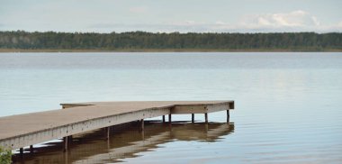 Orman nehri (göl) güneşli bir günde. Ahşap iskele. Clea gökyüzü, kristal berrak suda yansıyor. Idyllic manzara, kırsal manzara. Doğa, ekoloji, eko-turizm, yürüyüş, ekoloji beldesi, yerel turizm