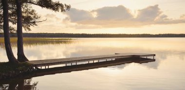 Orman Gölü (nehir) gün batımında. Ahşap iskele. Parlayan bulutlar, durgun ve berrak suda simetri yansımaları. Idyllic manzara. Doğa, ekoloji, ekolojik rezerv, eko-turizm, yürüyüş, tatiller
