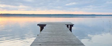 Orman Gölü (nehir) gün batımında. Ahşap iskele. Parlayan bulutlar, durgun ve berrak suda simetri yansımaları. Idyllic manzara. Doğa, ekoloji, ekolojik rezerv, eko-turizm, yürüyüş, tatiller