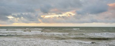 Gün batımında Baltık kıyılarından panoramik manzara. Dramatik bulutlar, parlayan bulutlar, fırtınadan sonra altın güneş ışığı. Doğa, çevre, iklim değişikliği, kararsız hava