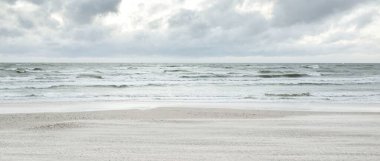 Baltık kıyıları (kum tepeleri) fırtınadan sonra gün batımında. Dramatik gökyüzü, parlayan bulutlar, rüzgar. Sonbahar manzarası. Doğa, çevre, ekoloji, kararsız hava, iklim değişikliği