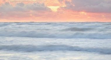 Deniz dalgaları ve sıçrama dokusu. Renkli gökyüzü suya yansıyor. Idyllic deniz manzarası. Kavramsal görüntü, uzun pozlama. Resimli bir manzara var. Arkaplan, duvar kağıdı, doğal desen, grafik kaynakları
