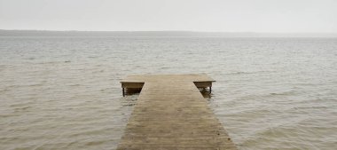 Yoğun bir siste orman nehri (göl). Ahşap iskele. Kasvetli gökyüzü, yağmur. Bulutlu bir gün. Idyllic manzara, kırsal manzara. Doğa, ekoloji, eko-turizm, yürüyüş, ekoloji beldesi, yerel turizm