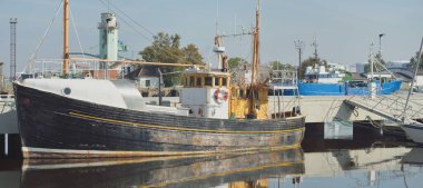 Eski bir ahşap klasik Kuzey Denizi balıkçı teknesi yat limanındaki bir rıhtıma demirlemiş. Denizcilik gemisi, ulaşım, geleneksel zanaat, sanayi