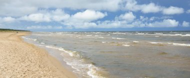 Güneşli bir günde Baltık Denizi kıyısı. Kumsal, kum tepeleri. Fırtınadan sonra dramatik gökyüzü, parlayan bulutlar.. Doğa, tatiller, eğlence. eko turizm