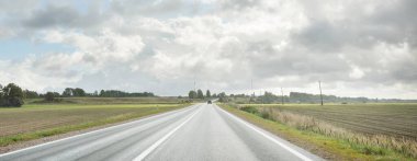 Tarlalar ve orman boyunca (asfalt yol) yol. Arabadan bak. Dramatik fırtına bulutları. Seyahat yerleri, rotalar, tatiller, lojistik, uzak yerler