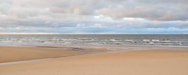Gün batımında Baltık kıyısı. Kumsal manzarası (kum tepeleri). Dramatik günbatımı gökyüzü, parlayan bulutlar. Idyllic manzara. Doğa, tatiller, eğlence. Çevre turizmi. Panoramik görünüm
