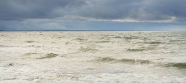 Fırtına sırasında Baltık Denizi. Dramatik gökyüzü, karanlık, parlak bulutlar. Dalgalar, su sıçramaları. Idyllic deniz manzarası. İklim değişikliği, doğa, kararsız hava, ekoloji