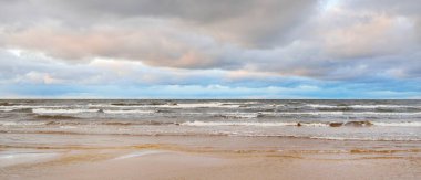 Gün batımında Baltık kıyısı. Kumsal manzarası (kum tepeleri). Dramatik günbatımı gökyüzü, parlayan bulutlar. Idyllic manzara. Doğa, tatiller, eğlence. Çevre turizmi. Panoramik görünüm