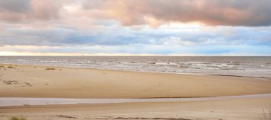 Baltic sea shore at sunset. View from the beach (sand dunes). Dramatic sunset sky, glowing clouds. Idyllic landscape. Nature, vacations, recreation. eco tourism. Panoramic view