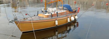 Modern klasik ahşap İsveçli yelkenli teknesi yat limanındaki bir iskeleye demirlemiş. Turizm, tatiller, boş zaman aktiviteleri, eğlence, yelkencilik temaları