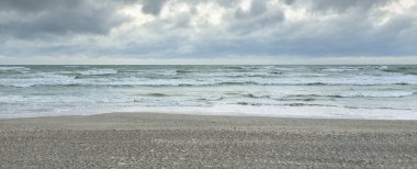 Baltık kıyıları (kum tepeleri) fırtınadan sonra gün batımında. Dramatik gökyüzü, parlayan bulutlar, rüzgar. Sonbahar manzarası. Doğa, çevre, ekoloji, kararsız hava, iklim değişikliği