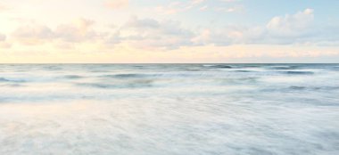 Deniz dalgaları ve sıçrama dokusu. Renkli gökyüzü suya yansıyor. Idyllic deniz manzarası. Kavramsal görüntü, uzun pozlama. Resimli bir manzara var. Arkaplan, duvar kağıdı, doğal desen, grafik kaynakları