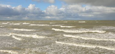 Fırtınadan sonra dramatik günbatımı bulutları altında Baltık Denizi. Dalgalar, su sıçratma. Destansı deniz manzarası. Kasırga, fırtına, sert hava, meteoroloji, ekoloji, iklim değişikliği, doğal olaylar
