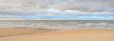 Gün batımında Baltık kıyısı. Kumsal manzarası (kum tepeleri). Dramatik günbatımı gökyüzü, parlayan bulutlar. Idyllic manzara. Doğa, tatiller, eğlence. Çevre turizmi. Panoramik görünüm