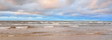 Gün batımında Baltık kıyısı. Kumsal manzarası (kum tepeleri). Dramatik günbatımı gökyüzü, parlayan bulutlar. Idyllic manzara. Doğa, tatiller, eğlence. Çevre turizmi. Panoramik görünüm