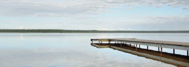 Orman nehri (göl) güneşli bir günde. Ahşap iskele. Clea gökyüzü, kristal berrak suda yansıyor. Idyllic manzara, kırsal manzara. Doğa, ekoloji, eko-turizm, yürüyüş, ekoloji beldesi, yerel turizm